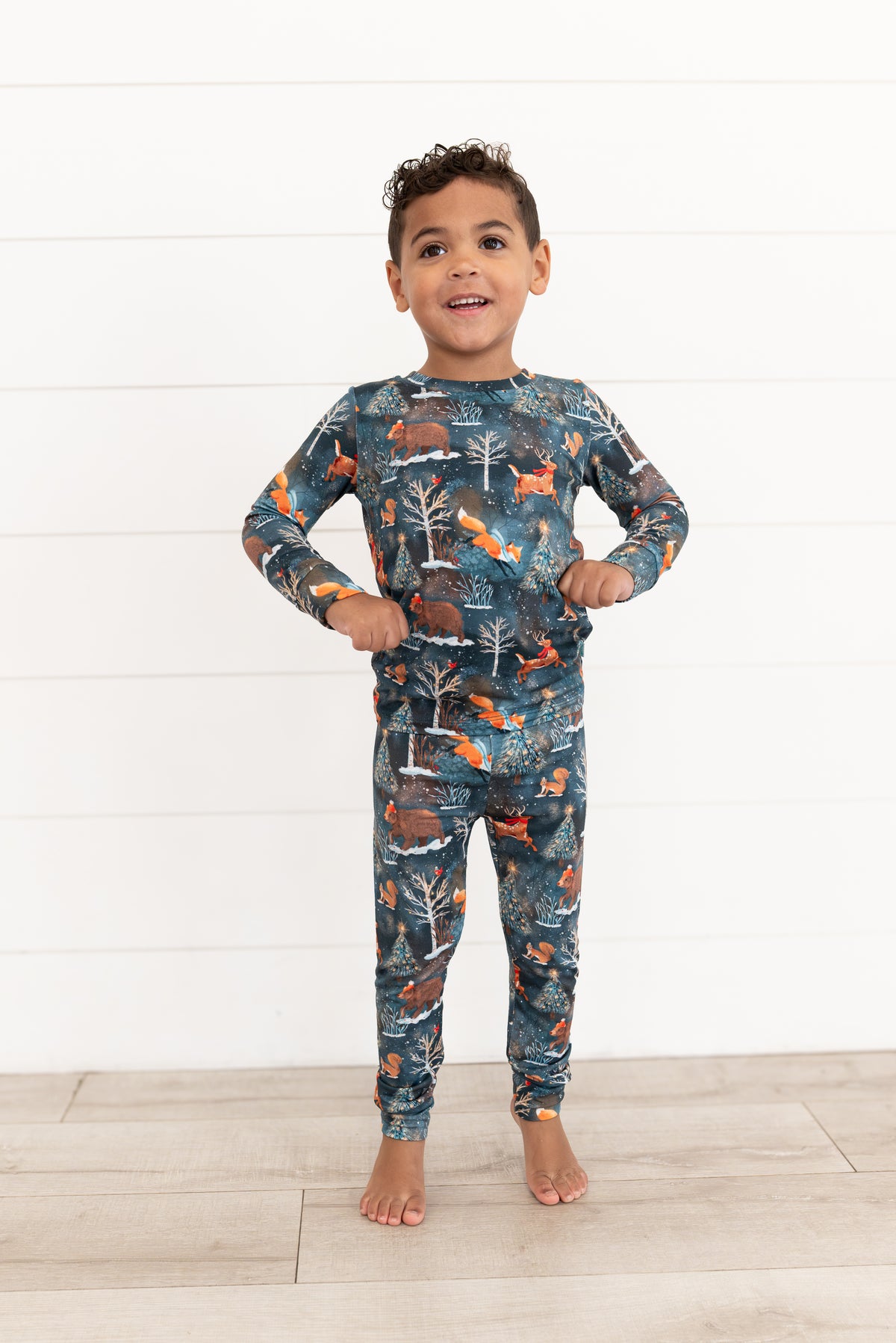 Young boy standing in Woodland Wonder bamboo kids two-piece pajamas in Christmas woodland print