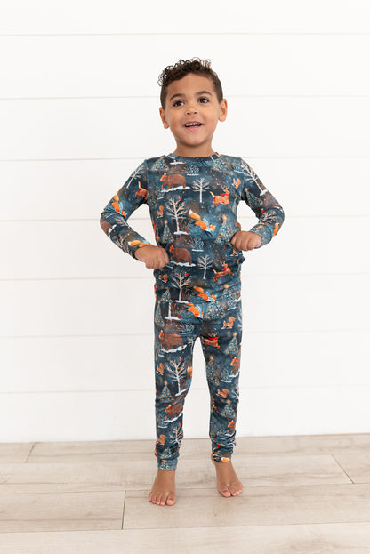 Young boy standing in Woodland Wonder bamboo kids two-piece pajamas in Christmas woodland print