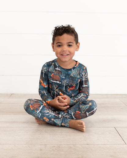Young boy sitting cross-legged wearing Woodland Wonder bamboo kids pajamas