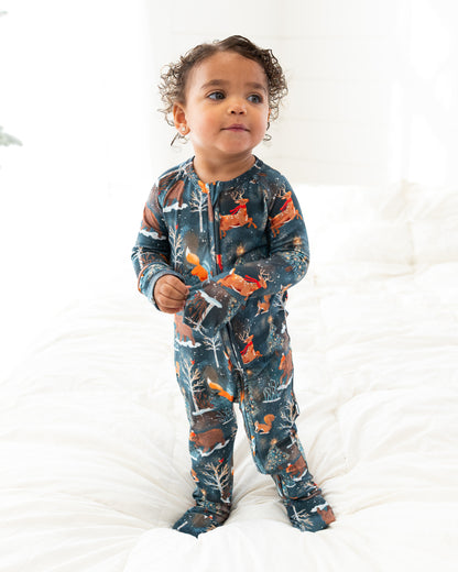 Toddler standing on a bed facing the camera in Woodland Wonder bamboo baby zip pajamas