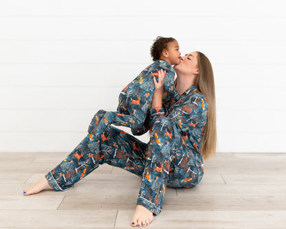 Mom sitting on the floor kissing a toddler, both in matching Woodland Wonder bamboo pajamas