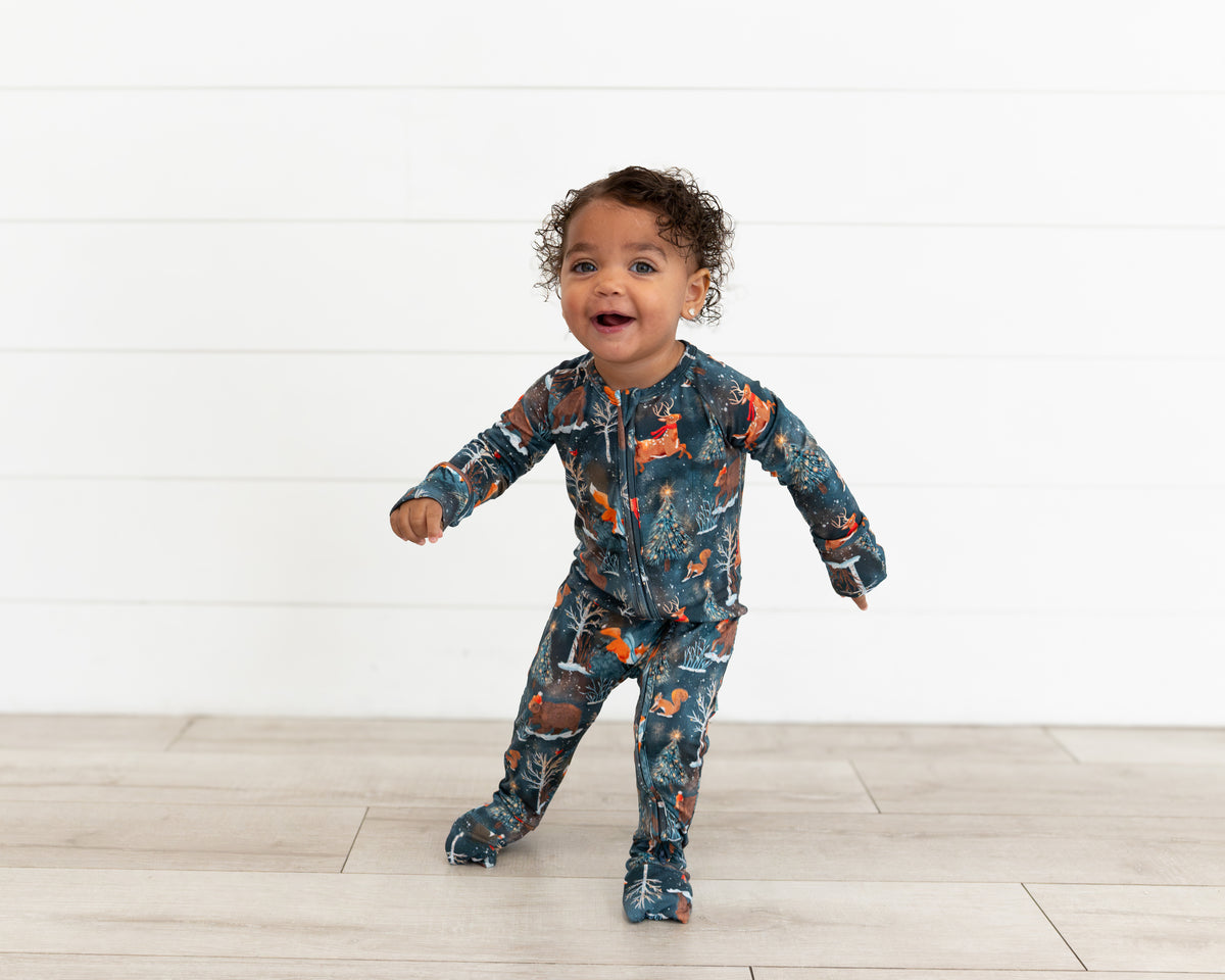 Happy toddler standing with arms out wearing Woodland Wonder bamboo baby zip pajamas