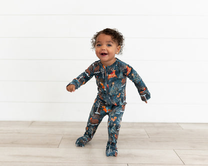 Happy toddler standing with arms out wearing Woodland Wonder bamboo baby zip pajamas
