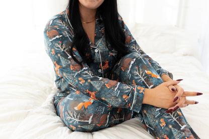 Woman sitting on a bed wearing the Woodland Wonder bamboo women's pajama set