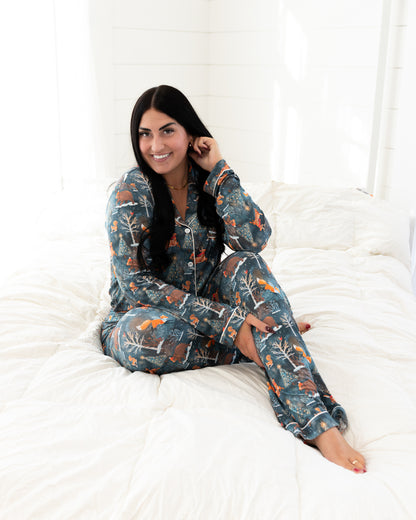 Woman sitting on a bed wearing the Woodland Wonder bamboo women's pajama set