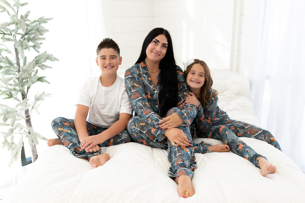 Family wearing matching Woodland Wonder bamboo Christmas pajamas on a bed