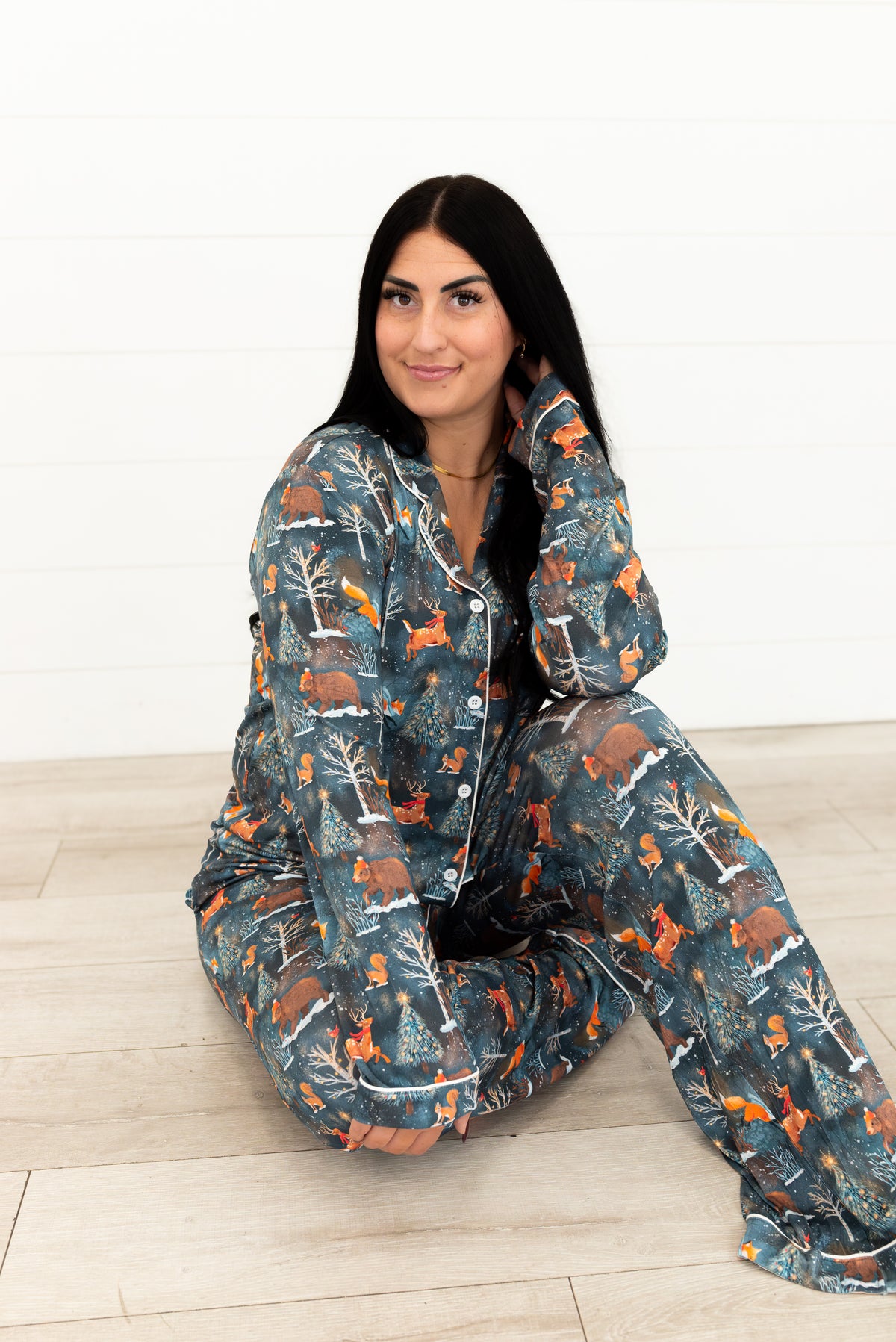 Woman sitting on the floor wearing Woodland Wonder bamboo women's pajama pants with matching shirt