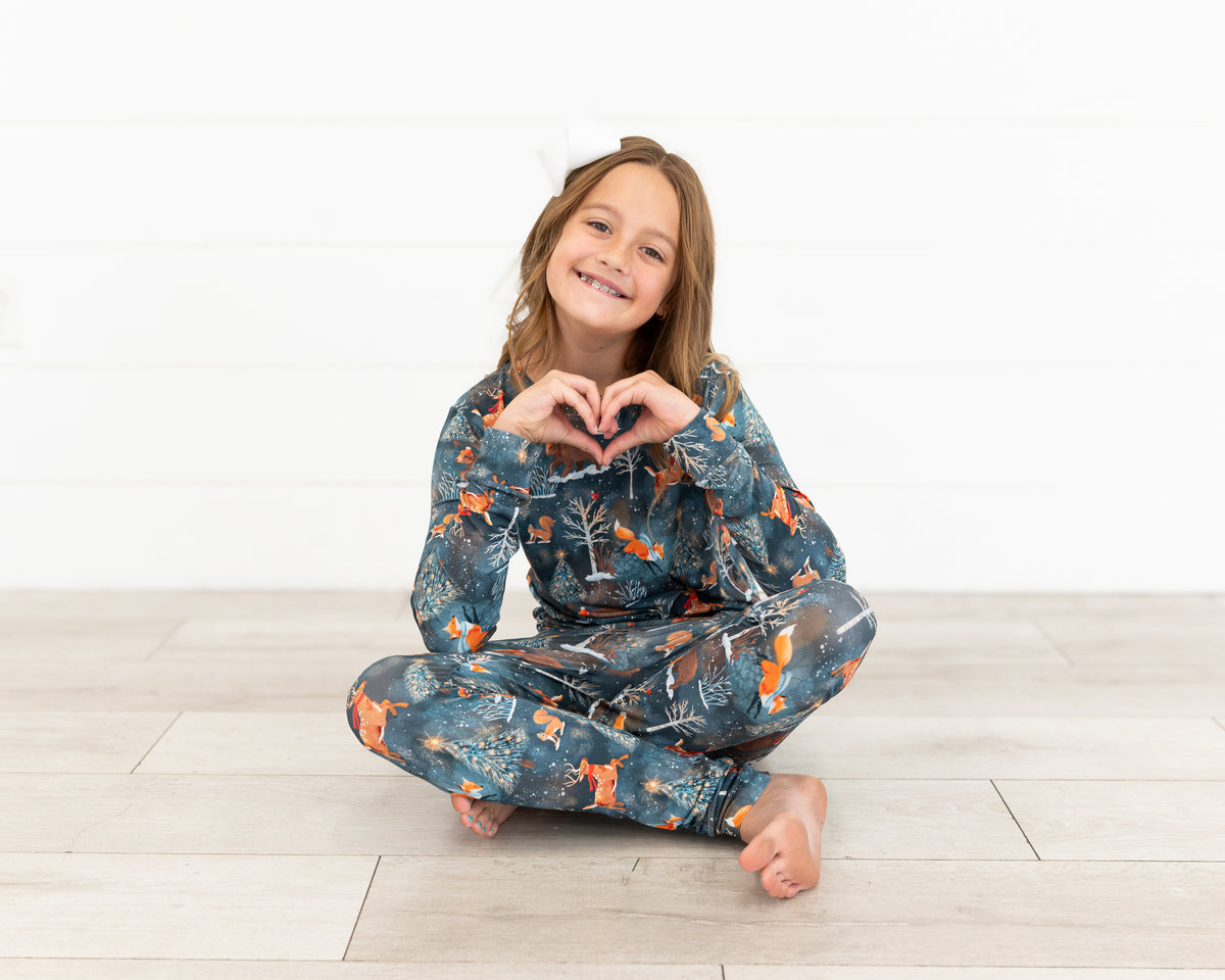 Teen girl making a heart with her hands wearing Woodland Wonder bamboo teen pajamas