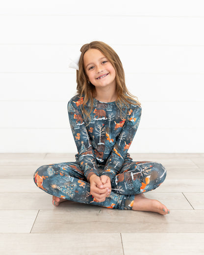 Teen girl sitting cross-legged wearing Woodland Wonder bamboo teen two-piece pajamas