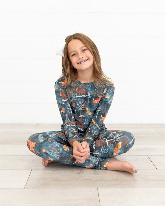 Teen girl sitting cross-legged wearing Woodland Wonder bamboo teen two-piece pajamas