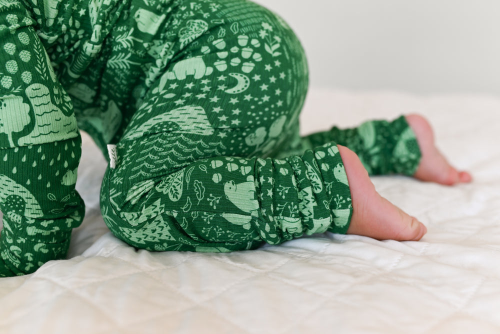 Little Bear Forest Ribbed Zip Pajamas – child in green bear print pajamas on white bed