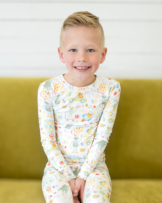 Child wearing a fun set of drawn pajamas sitting on a green couch.
