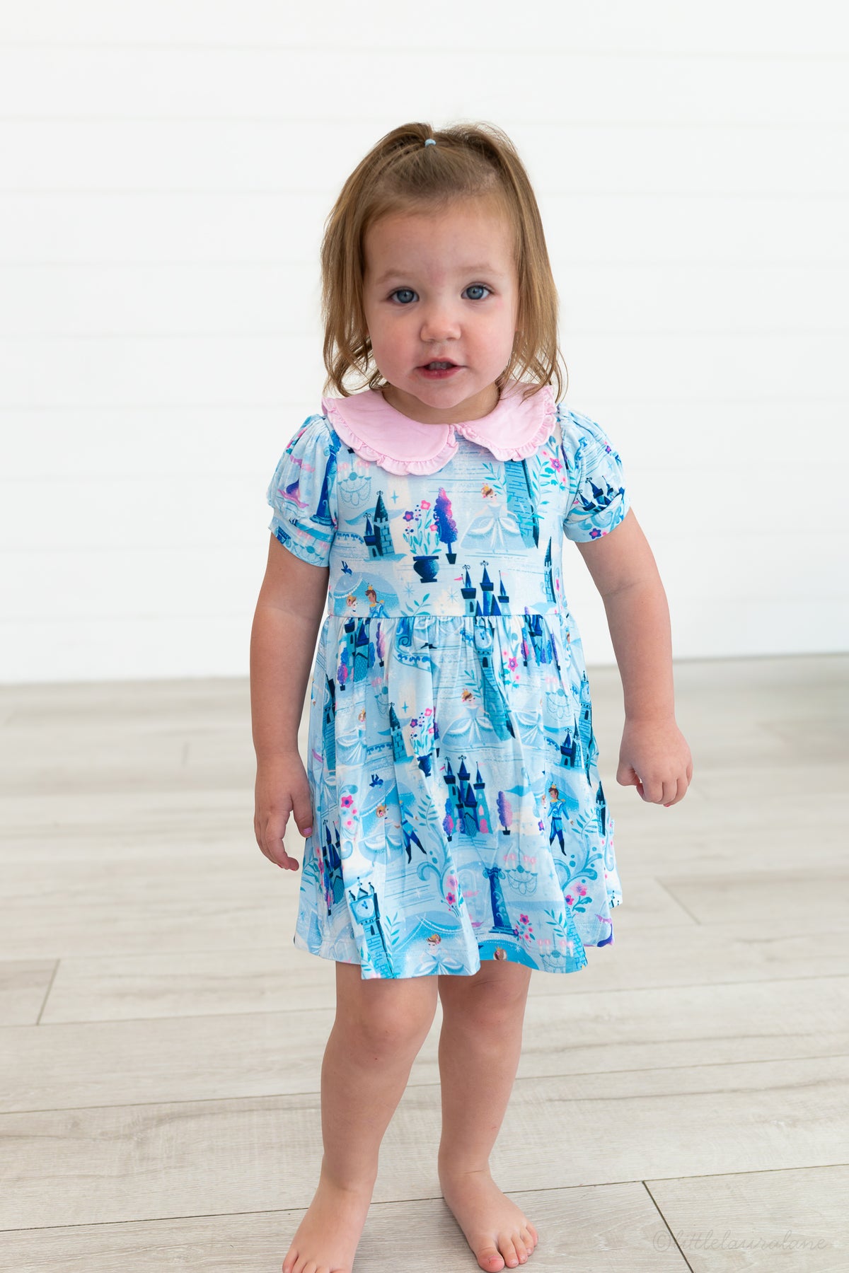 Baby Princess Dress – The Wish Collection – on-model, toddler in blue castle-print dress with pink Peter Pan collar