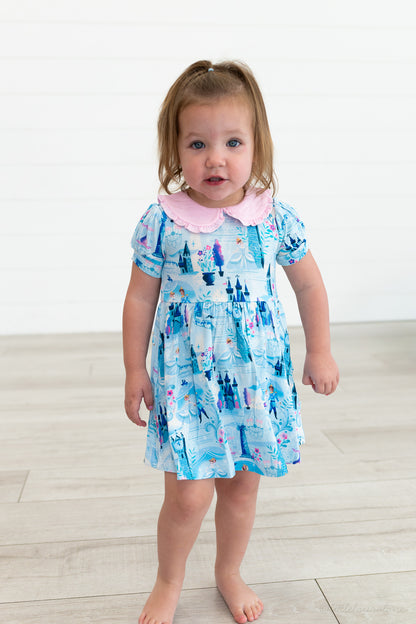 Baby Princess Dress – The Wish Collection – on-model, toddler in blue castle-print dress with pink Peter Pan collar