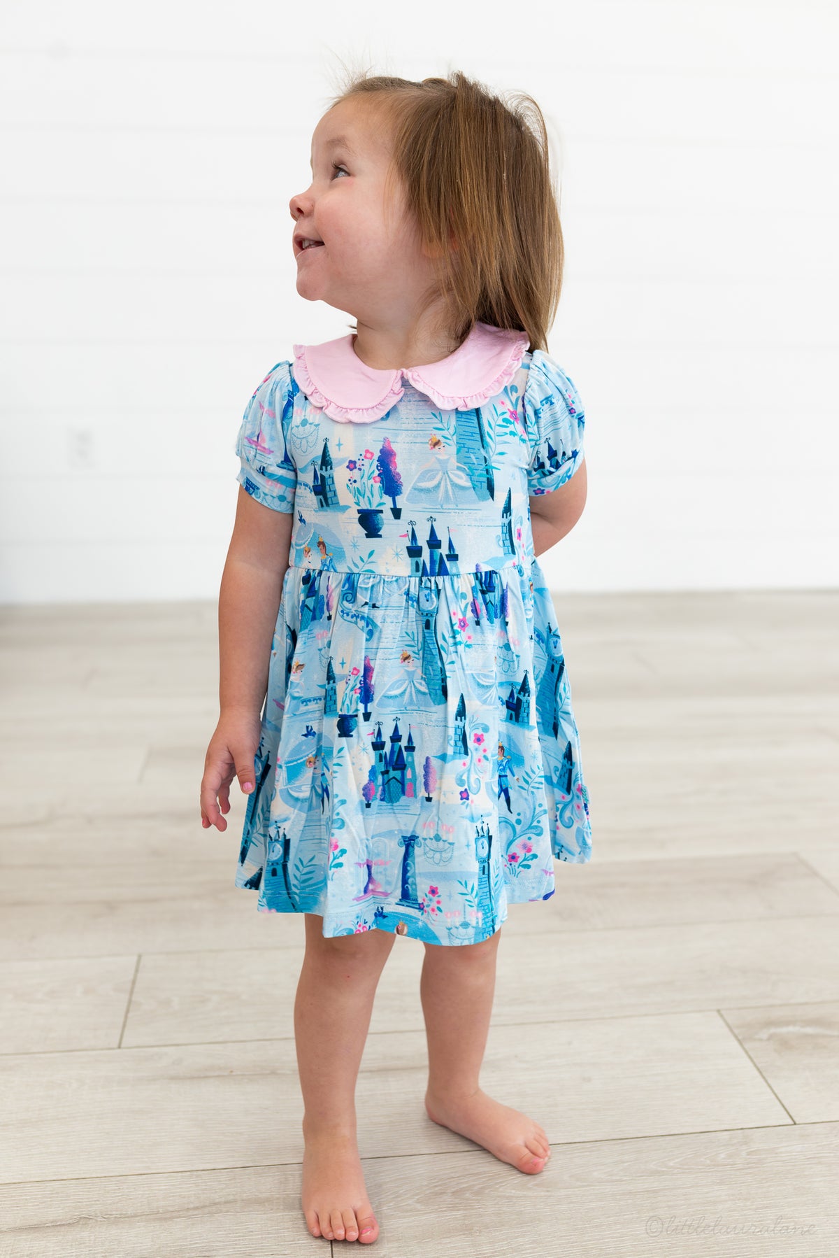 Baby Princess Dress – The Wish Collection – on-model, toddler in blue castle-print tiered dress with pink Peter Pan collar