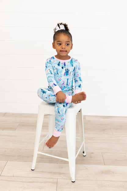 Two Piece Princess Pajama – The Wish Collection – on-model, girl sitting cross-legged on stool in blue castle-print pajamas