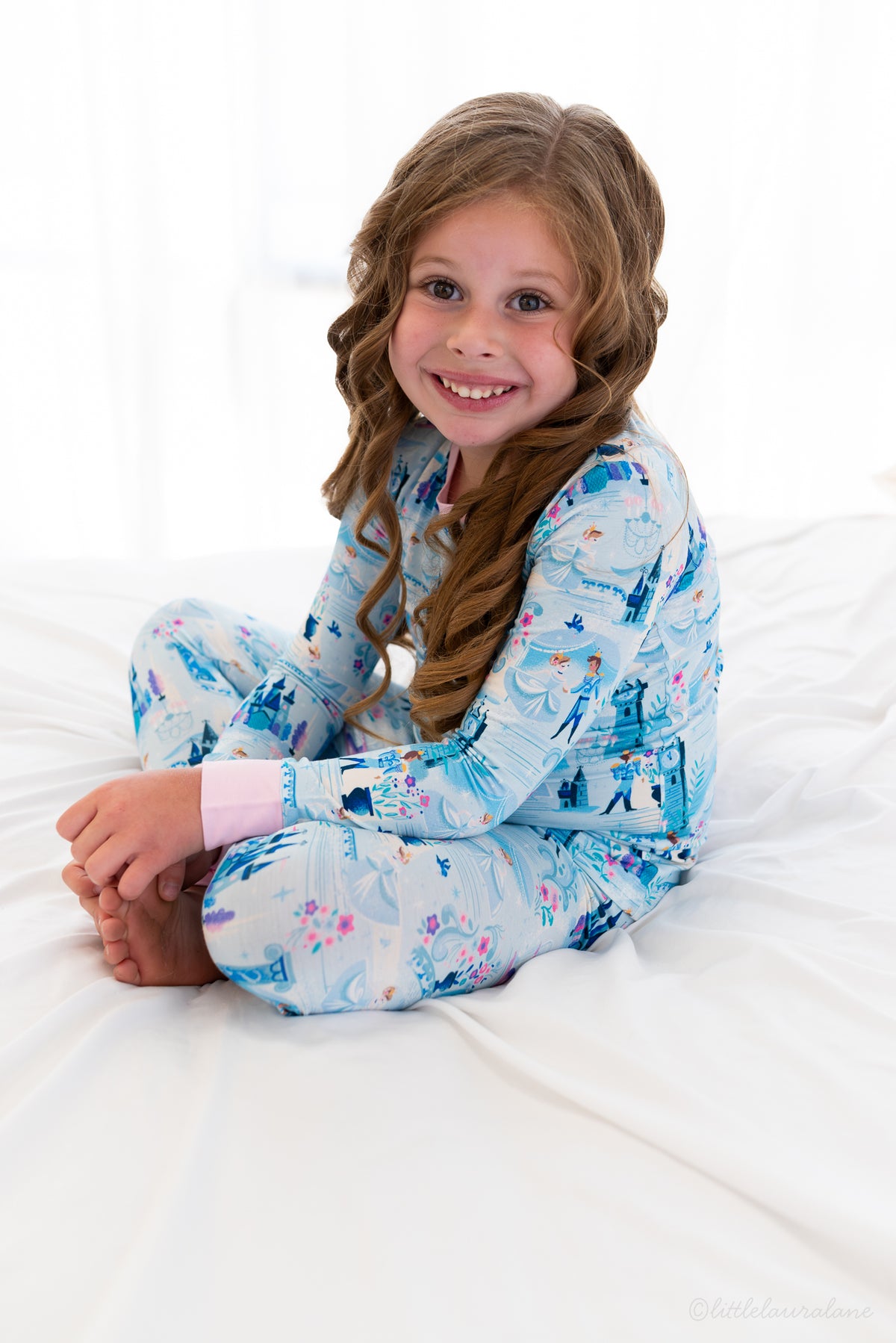 Two Piece Princess Pajama – The Wish Collection – on-model, girl sitting cross-legged in blue castle-print pajamas