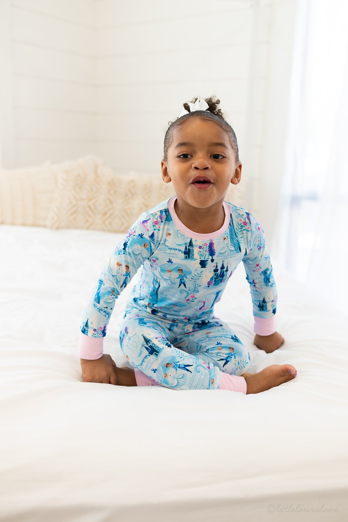 Two Piece Princess Pajama – The Wish Collection – on-model, child sitting on bed in blue castle-print pajamas