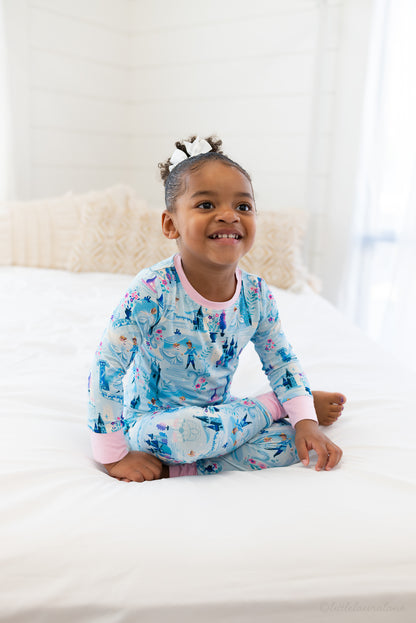 Two Piece Princess Pajama – The Wish Collection – on-model, child sitting on bed in blue castle-print pajamas
