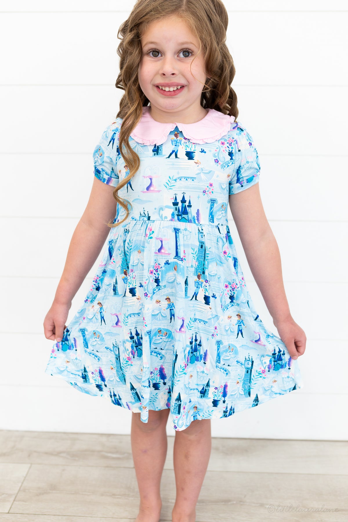 Girls Princess Dress with Shorts – The Wish Collection – on-model front view, girl holding skirt of blue castle-print dress