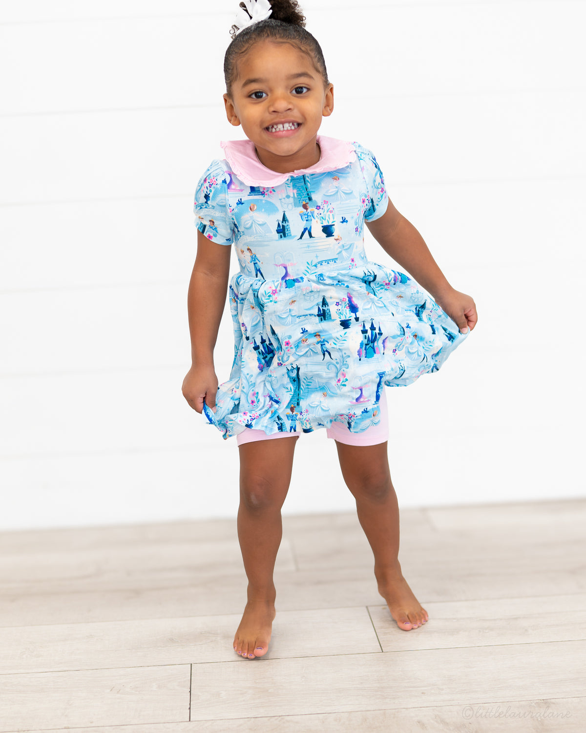 Girls Princess Dress with Shorts – The Wish Collection – on-model front view, child holding blue castle-print dress skirt