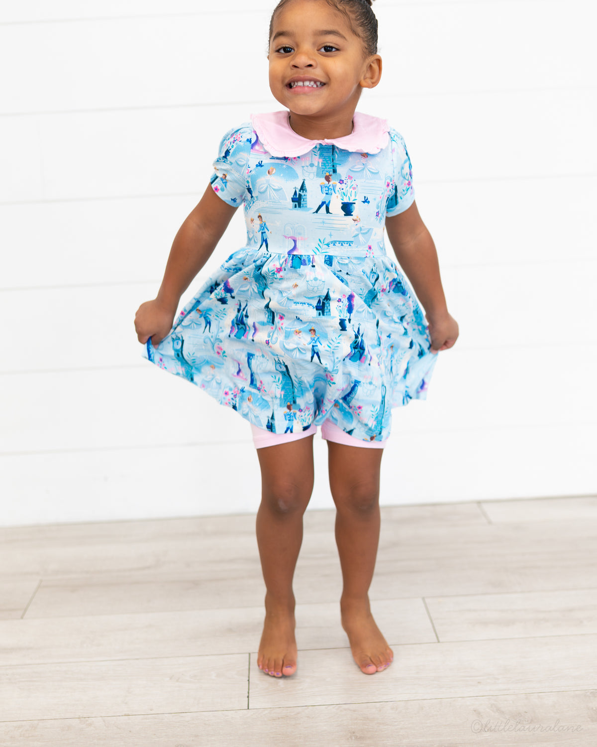 Girls Princess Dress with Shorts – The Wish Collection – on-model front view, girl holding blue castle-print dress skirt
