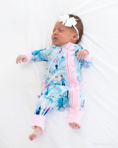 Baby Princess Pajama – The Wish Collection – on-model, sleeping newborn in blue castle-print zip pajama on white blanket