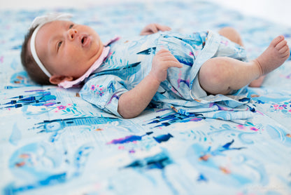 Baby Princess Dress – The Wish Collection – on-model, newborn lying on back in blue castle-print dress