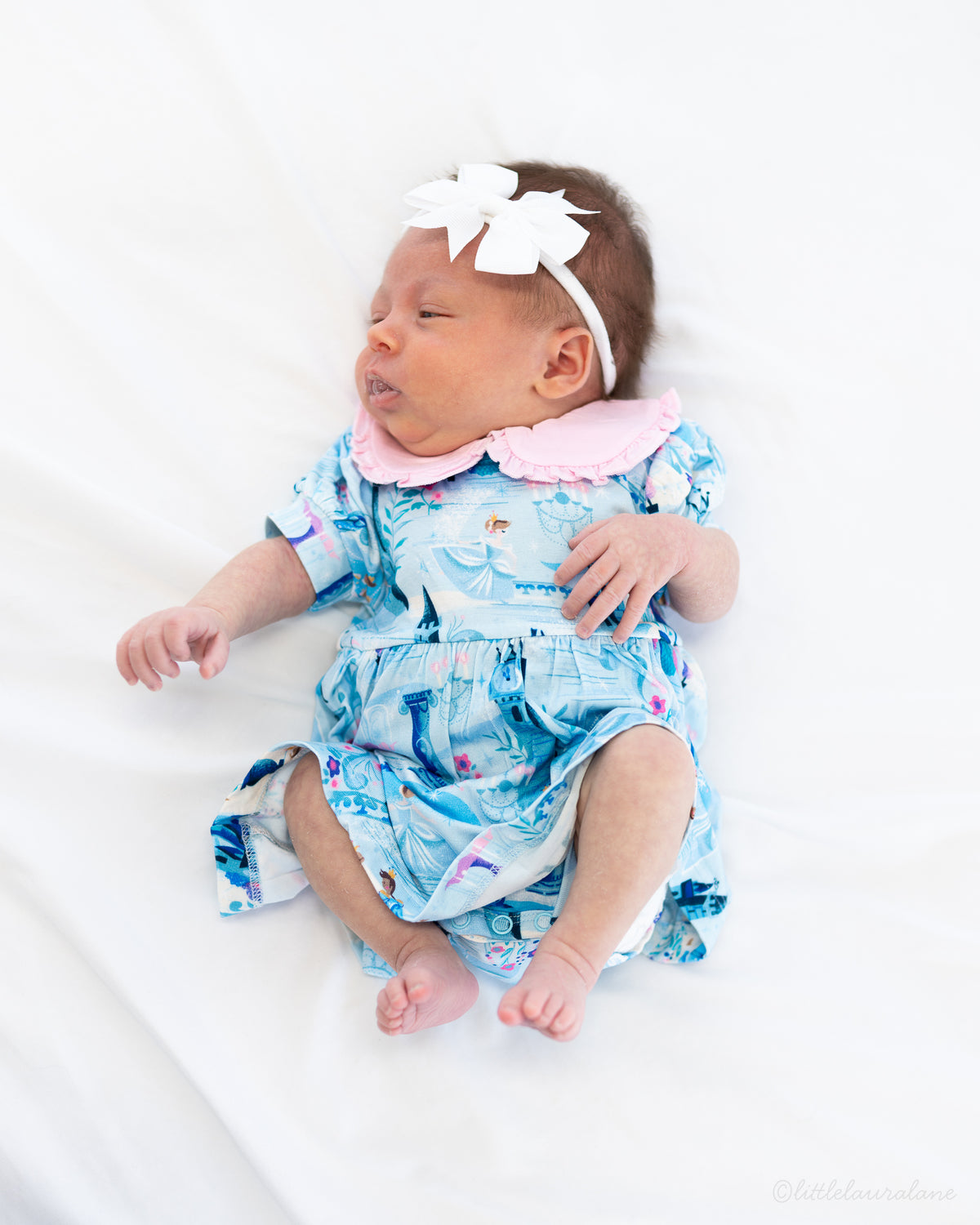 Baby Princess Dress – The Wish Collection – on-model, newborn in blue castle-print dress and bow headband on white blanket